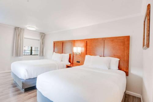 two beds in a hotel room with white sheets at Ramada by Wyndham Mountain View in Mountain View