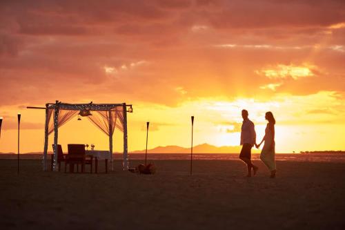 a couple walking on the beach at sunset at Hilton Fiji Beach Resort and Spa in Denarau