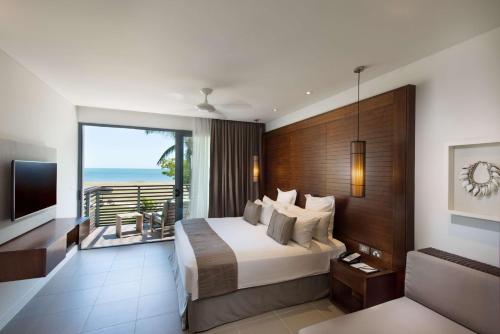 a bedroom with a bed and a balcony with the ocean at Hilton Fiji Beach Resort and Spa in Denarau