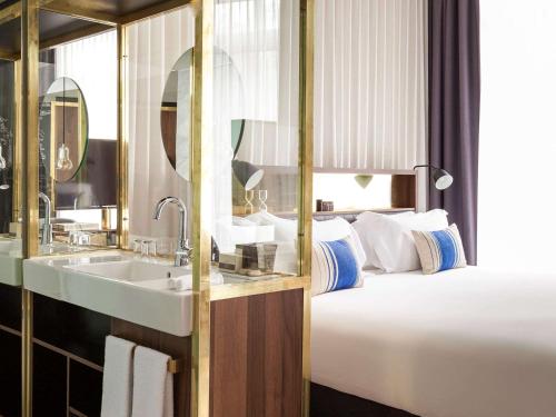 アムステルダムにあるINK Hotel Amsterdam - MGallery Collectionのベッドとシンク付きのホテルルーム