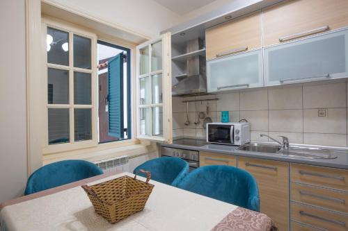 a kitchen with blue chairs and a table and a sink at Luxury Apartments Montesan in Sveti Stefan
