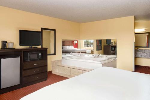 a bedroom with a bed and a tv and a tub at Baymont by Wyndham Cedar Rapids in Cedar Rapids