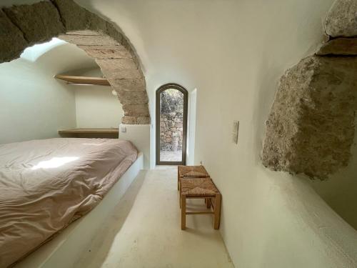 a bedroom with a bed and a chair and a window at Paleopoli Cave House in Kythira