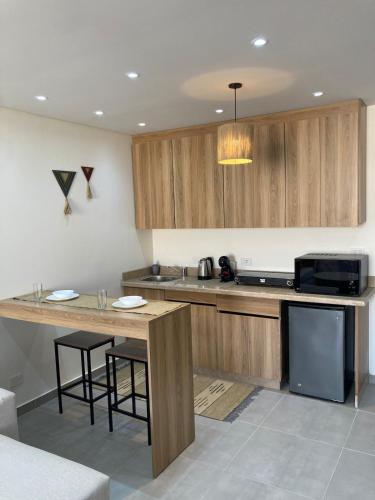 a kitchen with wooden cabinets and a counter with stools at First Row to Pyramids Studio in Kafrat Naşşār