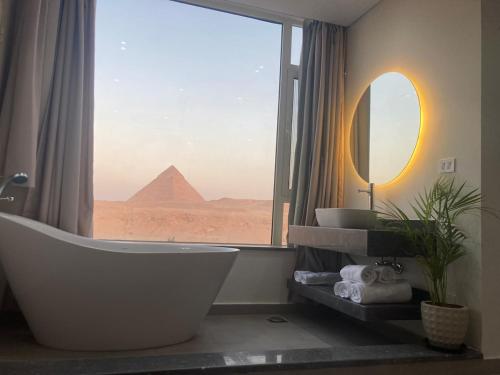 a bathroom with a tub and a view of the pyramids at First Row to Pyramids Studio in Kafrat Naşşār