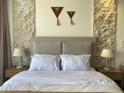 a bedroom with a white bed with two lamps at First Row to Pyramids Studio in Kafrat Naşşār