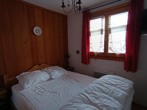 une chambre avec un lit et une fenêtre avec des rideaux rouges dans l'établissement Appartement cosy à 30m des pistes, plein sud avec terrasse - FR-1-445-145, à Montgenèvre