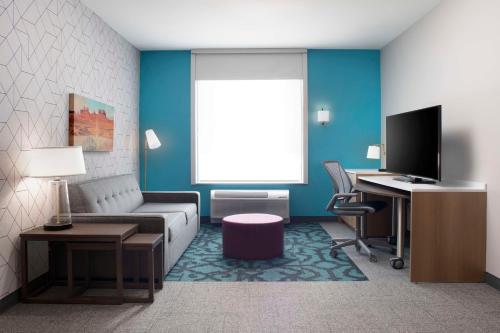 a living room with a couch and a desk at Home2 Suites By Hilton Albuquerque Airport in Albuquerque