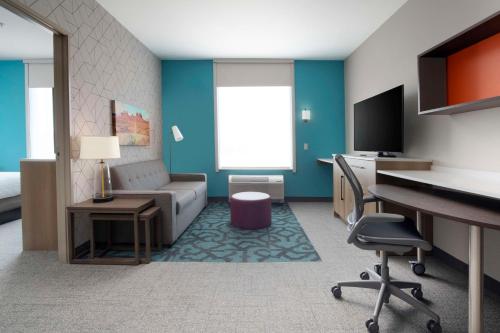 a room with a couch and a desk and a tv at Home2 Suites By Hilton Albuquerque Airport in Albuquerque