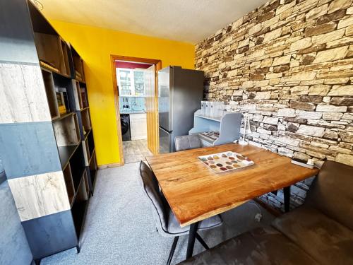 a dining room with a wooden table and a brick wall at The Maltings Retreat in Inverkeithing