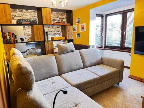 a living room with a couch and a tv at The Maltings Retreat in Inverkeithing