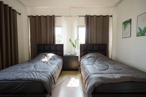 a bedroom with two beds and a window at CozyRooms Korat in Ban Nong Bo