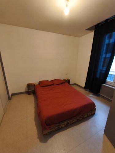 une chambre avec un lit rouge dans une pièce dans l'établissement Le provencal, à Puy-Guillaume