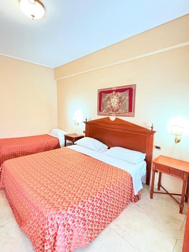 a hotel room with two beds and two tables at D'Angelo Palace Hotel in Mazara del Vallo