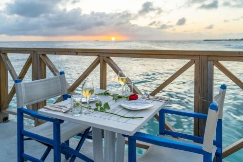 a table with two chairs and wine glasses on the ocean at The Rif At Mangrove Beach Corendon Curacao All-Inclusive, Curio by Hilton in Willemstad