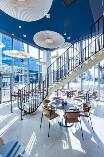 un restaurant avec des tables et des chaises et un escalier dans l'établissement Hilton Lille, à Lille
