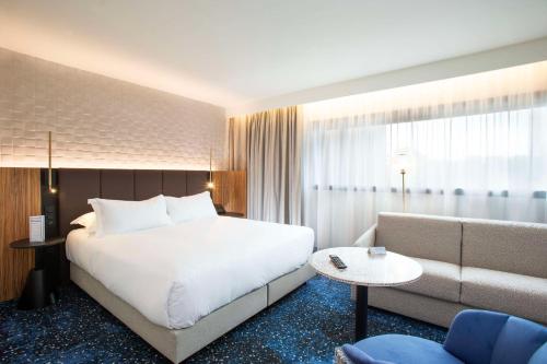 une chambre d'hôtel avec un grand lit et un canapé dans l'établissement Hilton Lille, à Lille