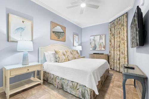 a bedroom with a bed and a night stand with a table at The Oasis at Orange Beach 2206 (Phoenix West II) in Orange Beach