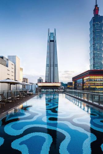 a swimming pool in front of a tall building at Humble House Taipei, Curio Collection by Hilton in Taipei