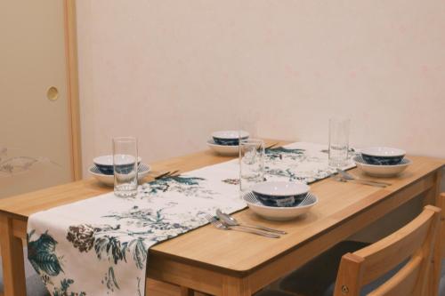a wooden table with plates and bowls on it at KOGO House大阪城公園徒歩圏内心斎橋電車で4分梅田電車で8分 in Osaka