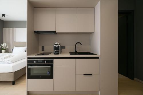 a kitchen with white cabinets and a sink next to a bed at Taunus Suites in Oberursel