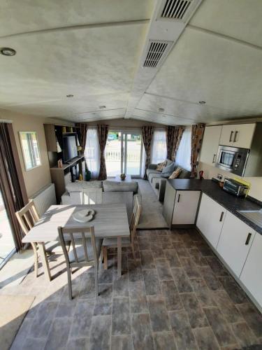 a kitchen and living room with a table and chairs at Sunset retreat caravan with large wrap around decking in Newquay