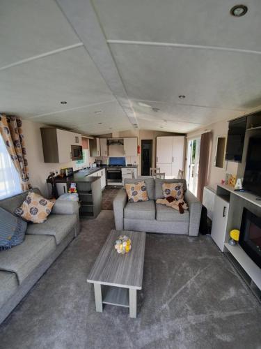 a living room with two couches and a table at Sunset retreat caravan with large wrap around decking in Newquay