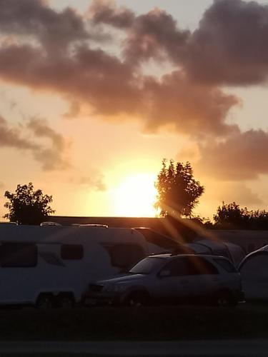 a sunset over a parking lot with vehicles parked at Sunset retreat caravan with large wrap around decking in Newquay