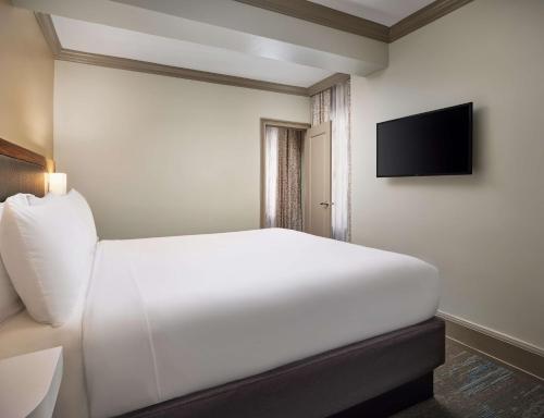 a bedroom with a white bed and a flat screen tv at Hampton Inn & Suites New Orleans Canal St. French Quarter in New Orleans