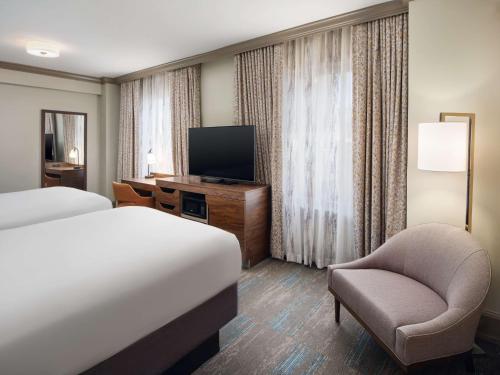 a hotel room with a bed and a chair and a television at Hampton Inn & Suites New Orleans Canal St. French Quarter in New Orleans