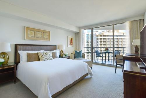 a bedroom with a large white bed and a balcony at Ka Laʻi Waikiki Beach, LXR Hotels & Resorts in Honolulu