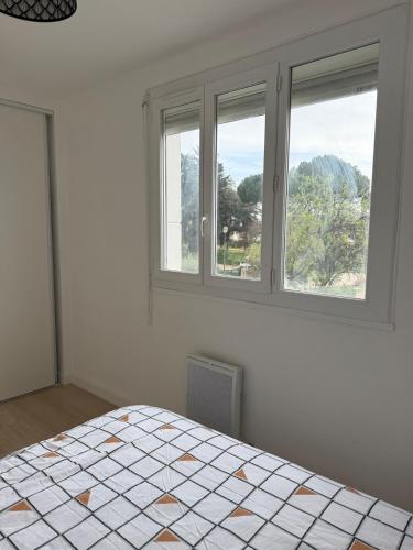 Cette chambre blanche dispose d'un lit et de deux fenêtres. dans l'établissement Appartement 75 metres carres proche gare et tram, à Montpellier