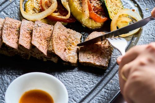 a plate of food with meat and vegetables and a bowl of sauce at Terradamari Resort & Spa Marina di Modica,Tapestry by Hilton in Marina di Modica