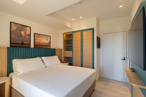 a bedroom with a white bed and a television at Terradamari Resort & Spa Marina di Modica,Tapestry by Hilton in Marina di Modica