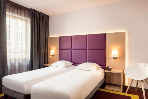 um quarto com uma cama grande e uma cabeceira de cama roxa em Aparthotel Adagio Paris Malakoff Chatillon em Malakoff
