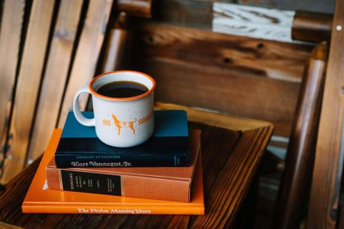 a cup of coffee sitting on top of three books at Graduate by Hilton Knoxville in Knoxville