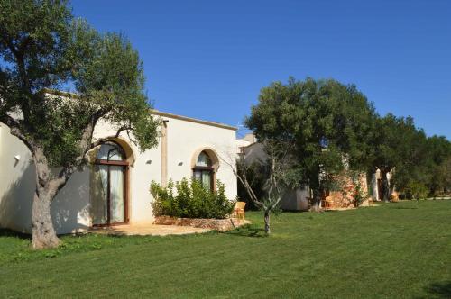 une maison blanche avec des arbres dans la cour dans l'établissement Masseria Le Celline, à Nardò