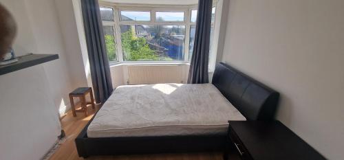 a bed sitting in a room with a window at Ritz place 3 in Northolt