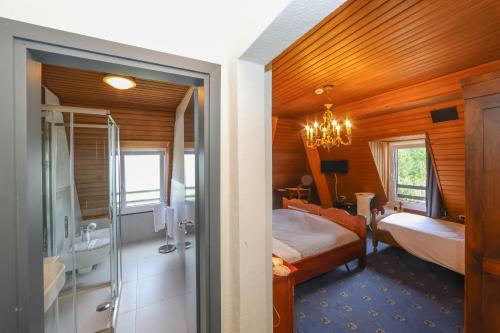 a bedroom with a bed and a bathroom with a shower at Hotel Regina del Bosco in Ronzone