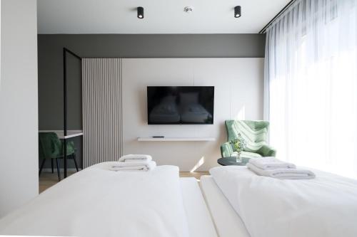 a bedroom with two beds and a tv on the wall at Taunus Suites in Oberursel