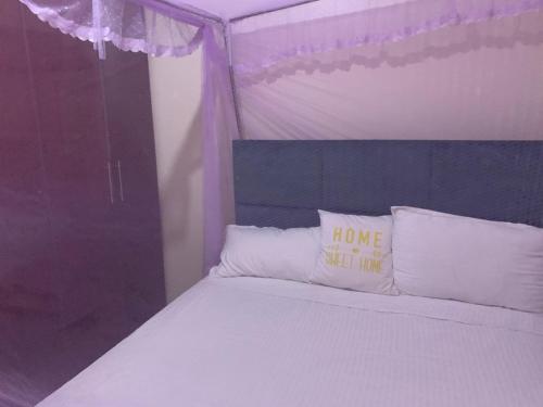 a bedroom with a bed with a home sweet inn pillow at Angie's palace in Syokimau