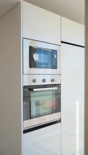 a white kitchen with an oven with a microwave at Front Beach Costa Caparica Lisbon in Costa da Caparica