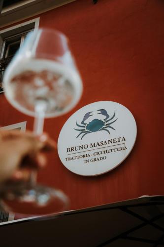 a person holding a wine glass in front of a sign at Ca’ Bruno Masaneta in Grado