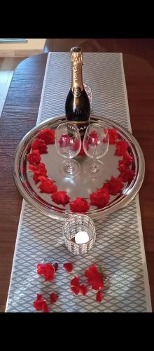 a glass tray with wine glasses and red roses on a table at Atpūtas māja Liepalejas in Stacija Vatrāne
