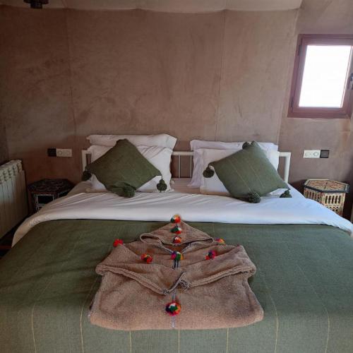 a blanket on a bed with a robe on it at Erg Chebbi Dunes Desert Camp in Merzouga