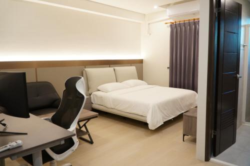 a bedroom with a bed and a desk with a computer at Hermit Crab Guesthouse in Hengchun