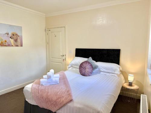a bedroom with a large white bed with a pink blanket at Pass the Keys Countryside Retreat in Reynoldston Gower, Sleeps 10 in Reynoldston