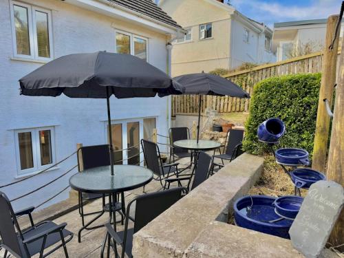two tables and chairs with umbrellas on a patio at Pass the Keys Countryside Retreat in Reynoldston Gower, Sleeps 10 in Reynoldston