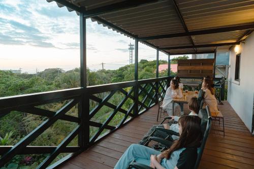 a group of people sitting at tables on a deck at 美ら海水族館まで車4分の一棟貸ヴィラちゅらジャングルリゾート in Motobu
