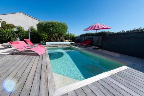 - une piscine avec 2 chaises roses et un parasol dans l'établissement Villa entière 14 couchages prés de la mer La Londe Les Maures Entre Hyères et Le Lavandou, à La Londe-les-Maures